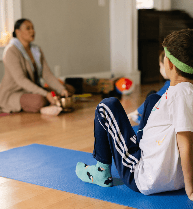 A child practicing yoga on a mat with an ARISE instructor
